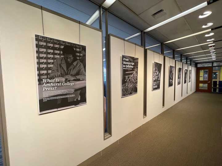 Black and white posters hanging in a row. The first has the title What Is Amherst College Press? The archival image shows a young Black man looking through a card catalog.
